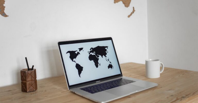 A minimalist desk setup with a laptop showing a world map screen and a mug, set against a wall map backdrop.